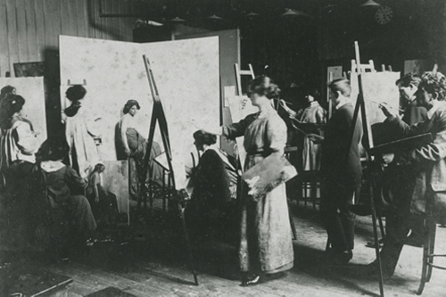 A historical photo of women painting on easels in an art classroom.